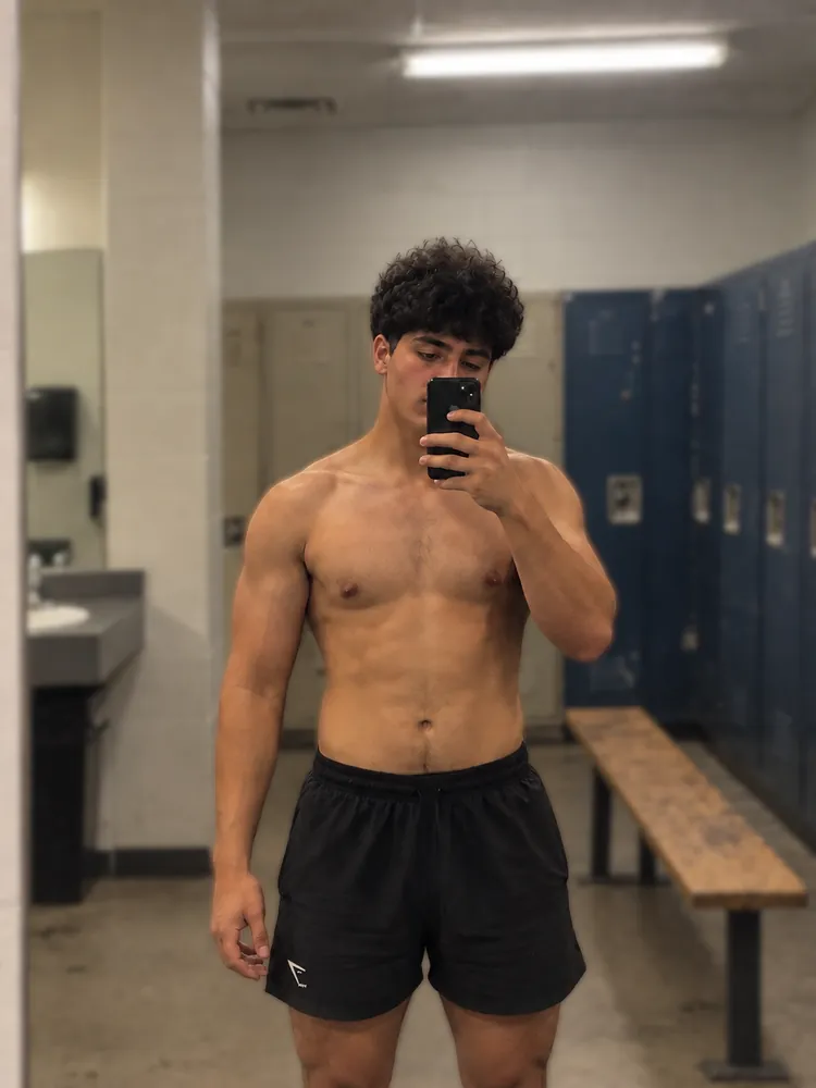 Zero To Growth member taking a mirror selfie in a locker room, with defined shoulders and arms